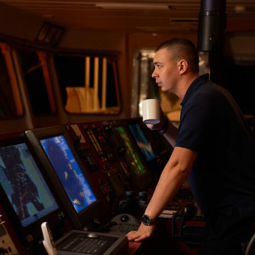 Navigation officer. Pilot on a bridge of a vessel underway with radio station and binocular in hands